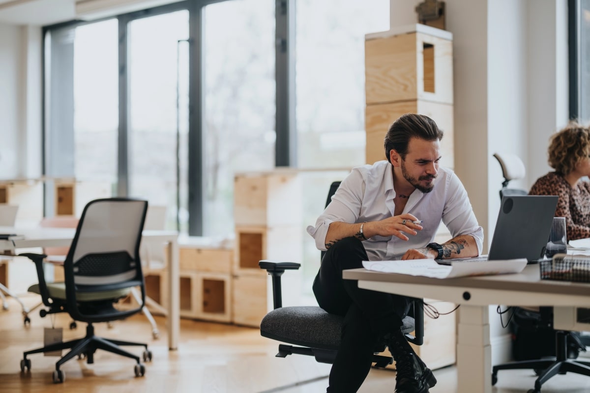 Why You’ll Love Upgrading to a Contemporary Desk Chair This Year 6 Man working in a modern office while sitting in a contemporary desk chair at his workstation.