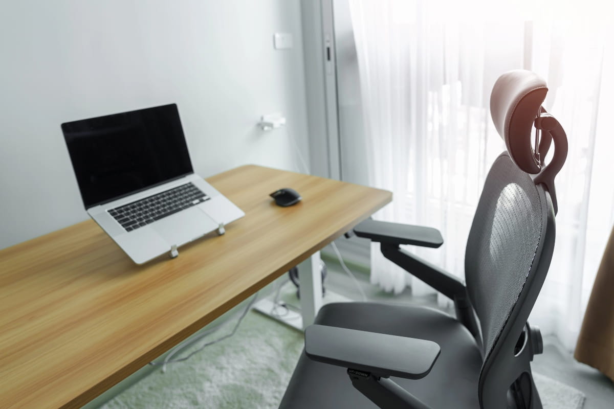 Desk, laptop and ergonomic chair designed for better posture during work.