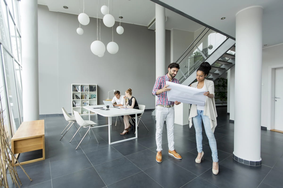 Office workers standing and reviewing plans during a movement break.