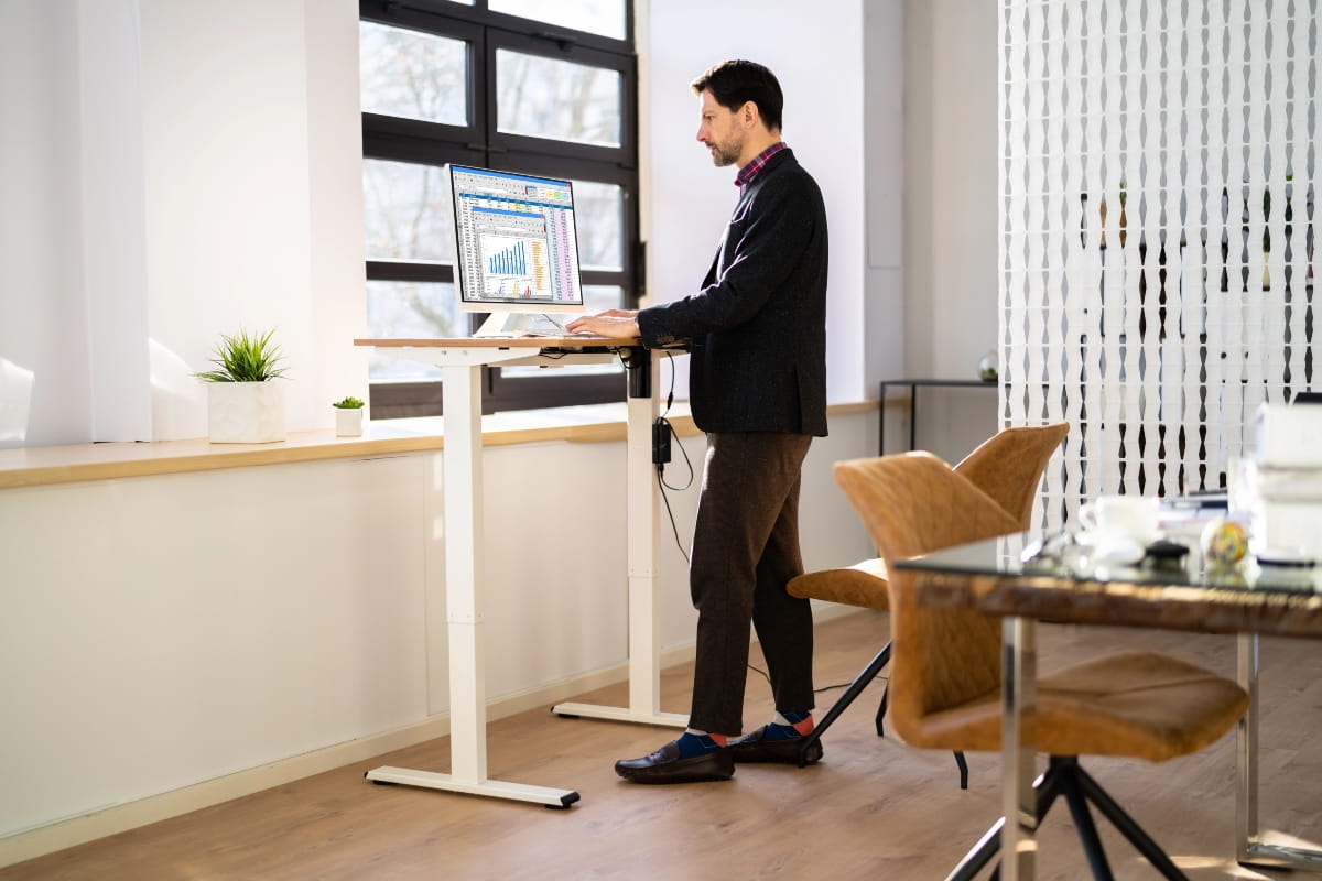 Person standing with upright posture at an adjustable office desk.