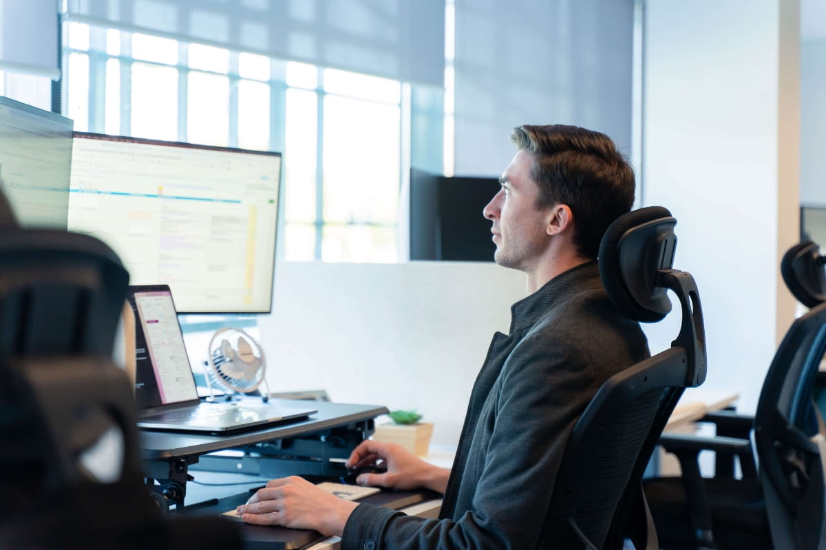 Is Standing Better Than Sitting? Finding the Right Balance at Work 6 Worker using an ergonomic office chair with headrest and monitor.