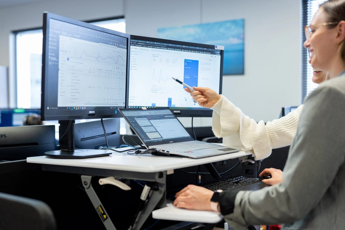 Is Standing Better Than Sitting? Finding the Right Balance at Work 2 Two office workers using a sit-stand desk with multiple monitors.