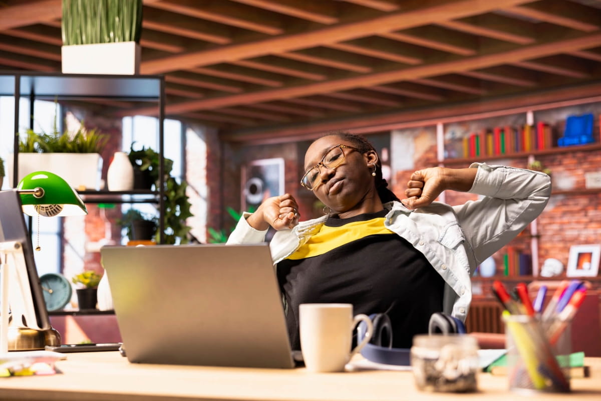 Is Standing Better Than Sitting? Finding the Right Balance at Work 3 Office worker stretching at a desk after sitting for too long.
