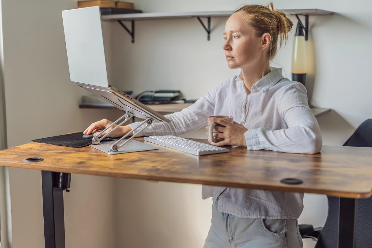 Standing Desk Posture: How to Stand Comfortably All Day 4 Person working at a desk that appears too high.