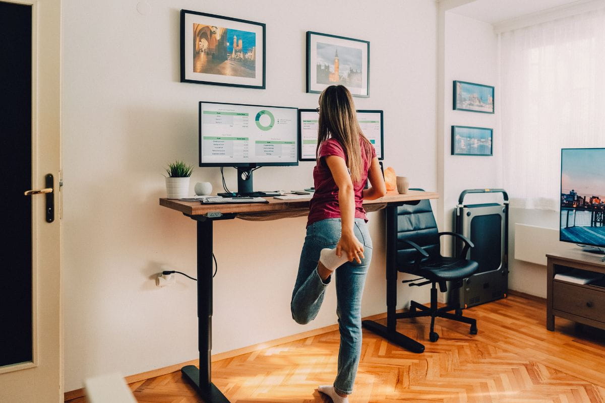 Standing Desk Posture: How to Stand Comfortably All Day 1 Standing desk posture example showing a person alternating movement while working at a home office desk.
