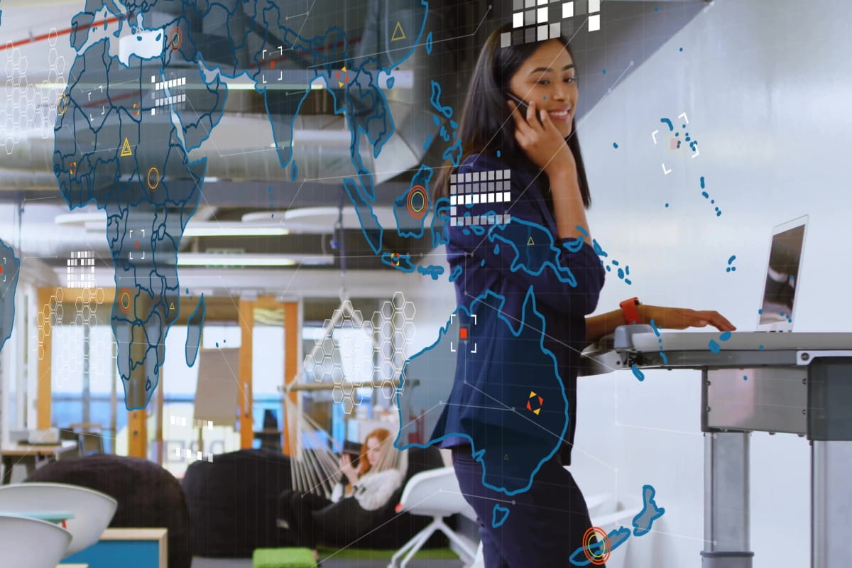 Office worker using a standing desk during the workday with digital map graphics overlaid.