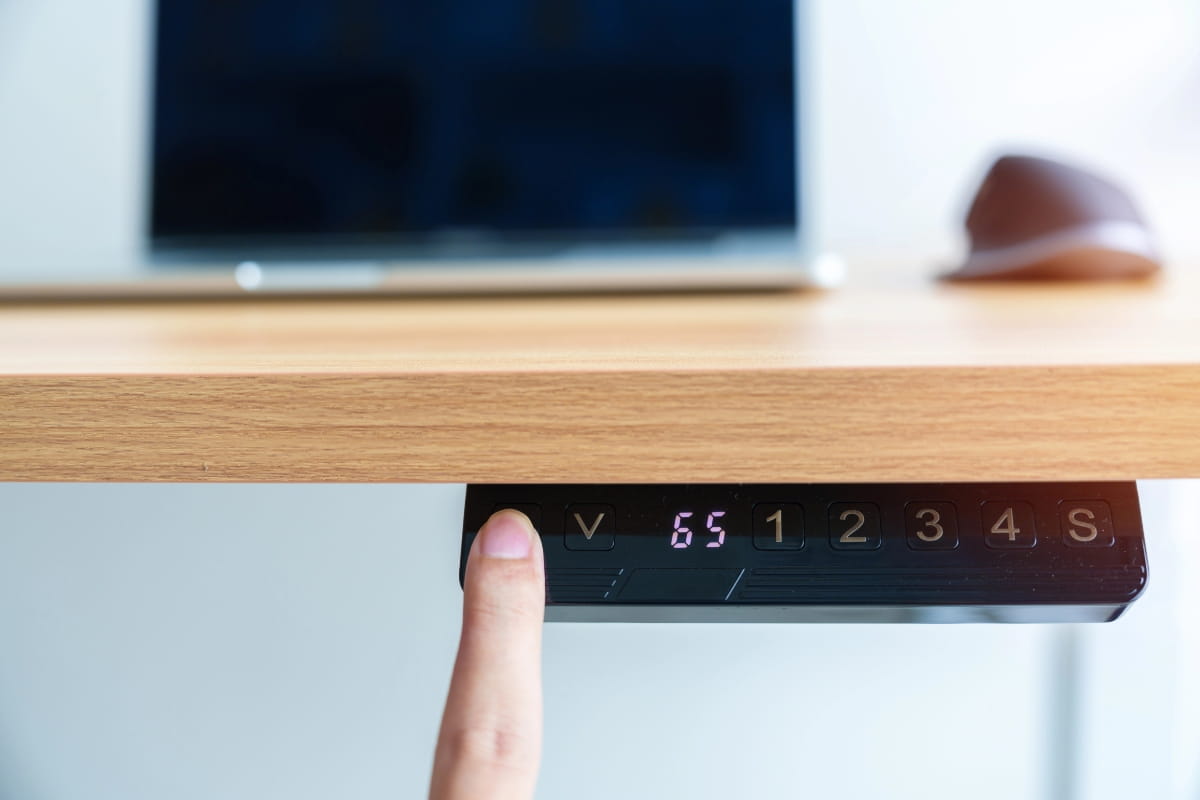 Standing Desk Height: How to Find the Right Setup for You 4 Finger pressing a height control button under a standing desk.