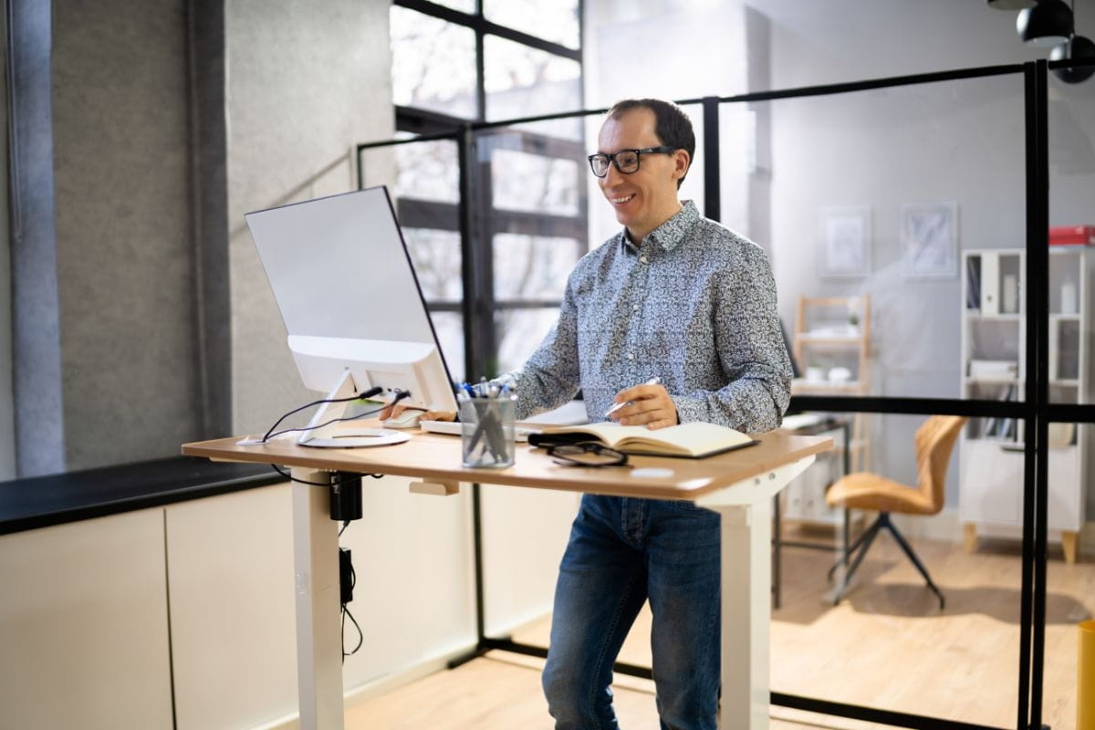 Standing Desk Height: How to Find the Right Setup for You 3 Office worker standing at a height adjustable desk.