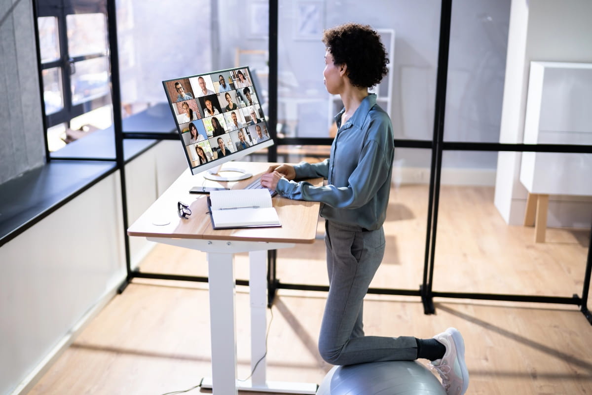 Standing Desk Height: How to Find the Right Setup for You 2 Office worker at an adjustable desk with a monitor and notebook, demonstrating a practical standing desk height for daily tasks.
