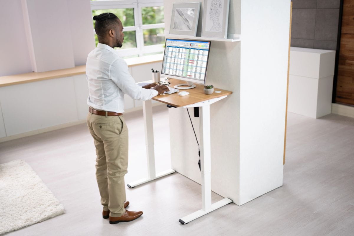 5 Standing Desk Mistakes That Hurt Your Ergonomics 3 Office worker standing at a height-adjustable desk, demonstrating an ergonomic standing workstation setup.