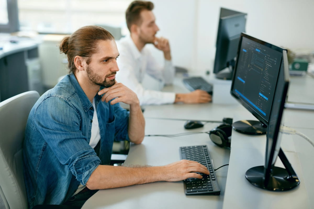 How to Transition to a Standing Desk Without Pain or Fatigue 2 Office worker seated at a dual-monitor workstation.