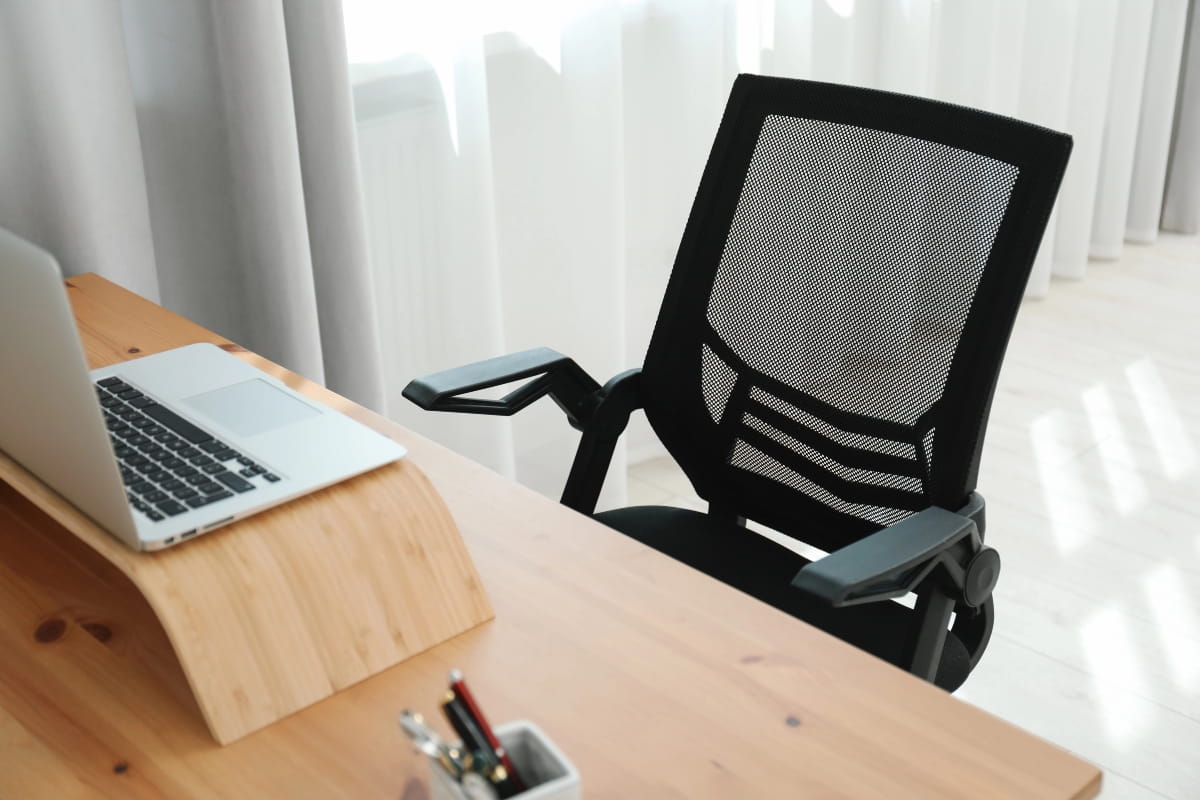 5 Standing Desk Mistakes That Hurt Your Ergonomics 4 Ergonomic mesh office chair positioned beside a desk with a laptop, supporting comfortable seated work between standing periods.