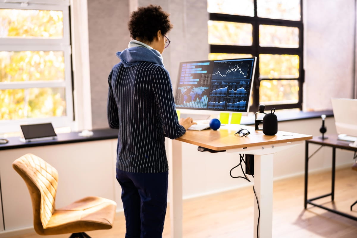 How to Transition to a Standing Desk Without Pain or Fatigue 4 Office worker standing at a height-adjustable desk.