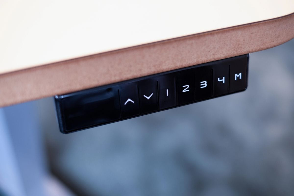 Close-up of an electric standing desk control panel with height adjustment buttons and four programmable memory settings.