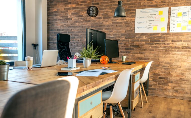 Interior of industrial style coworking office with various work stations. and office chairs.