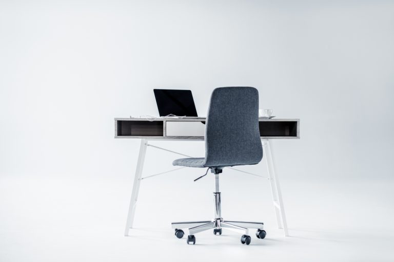 White room with desk with an armless office chair.