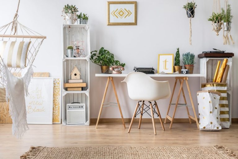 A stylish home office desk with functional storage solutions, including stacked wooden crates and hanging planters.
