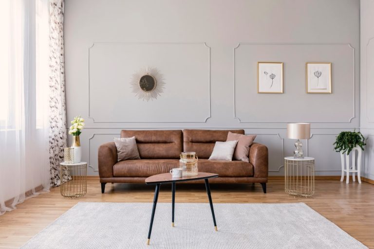 Living room with brown leather sofa, coffee table and pot plant.