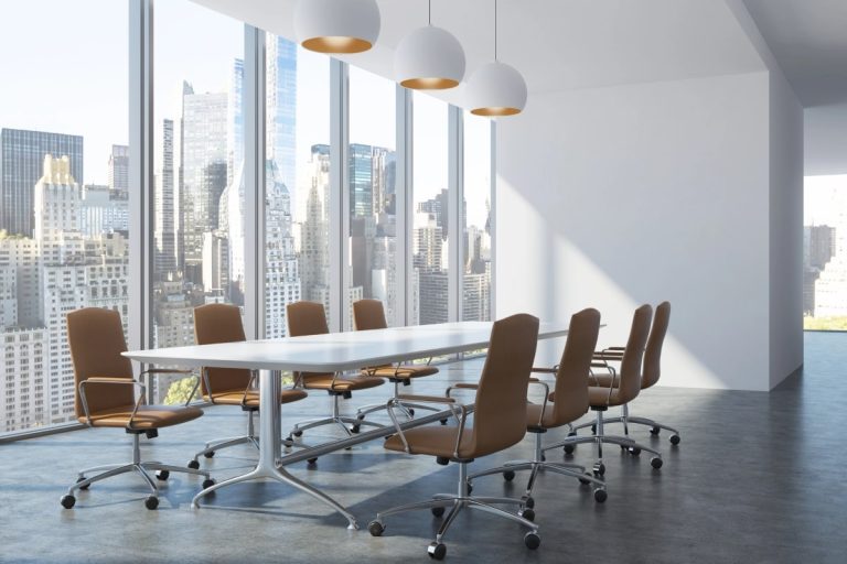 An office boardroom, with large windows, long table and tan leather chairs.