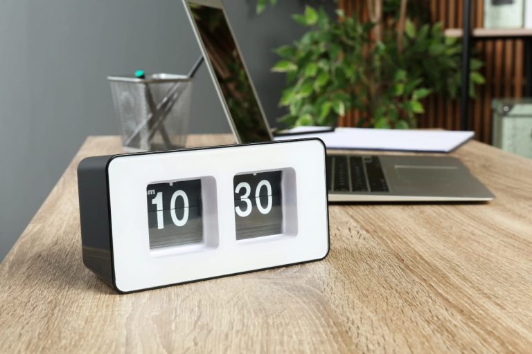 Flip clock on a workspace highlighting how long should you stand at a standing desk during the day.