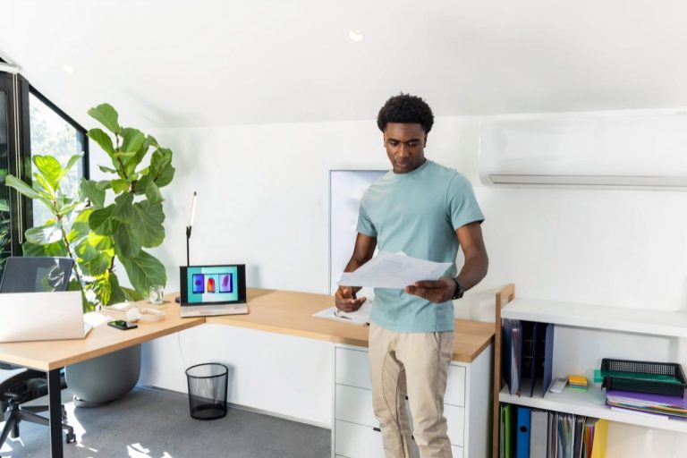 Spacious L-shaped standing desk with a wooden desktop, laptop and office accessories in a naturally lit workspace.