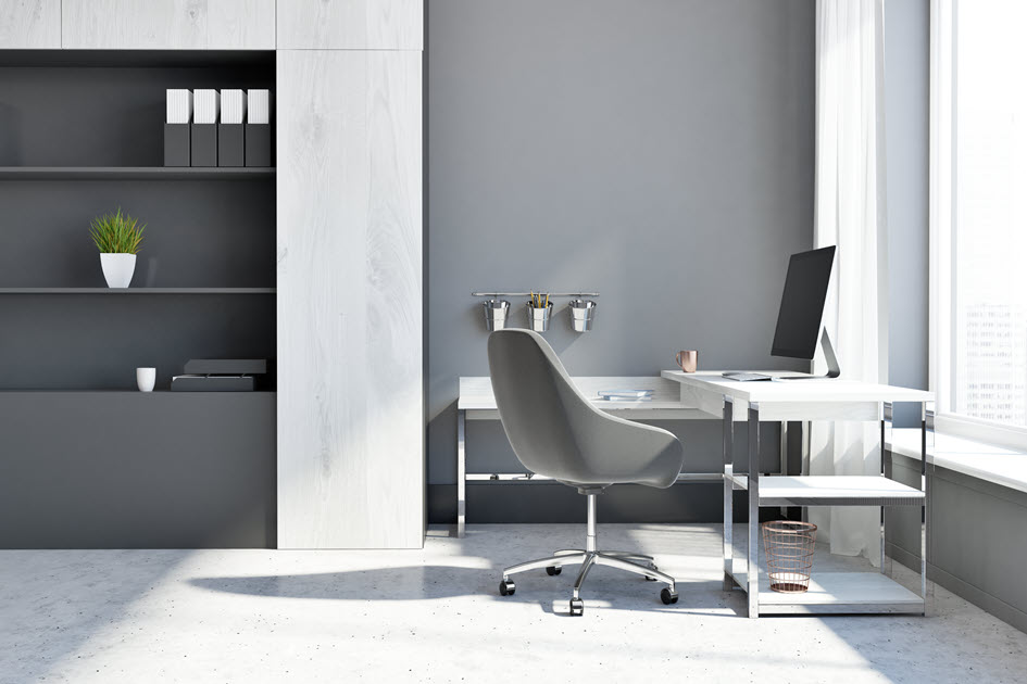 Modern office interior with a white corner workstation desk and grey chair.