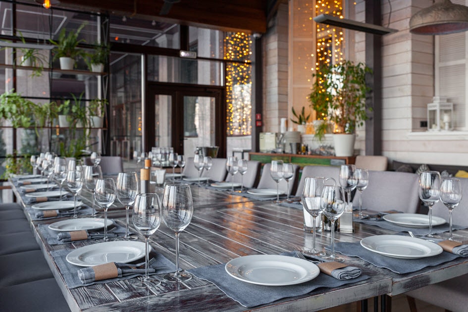 A modern alfresco restaurant with grey chairs and rustic table set for a banquet.