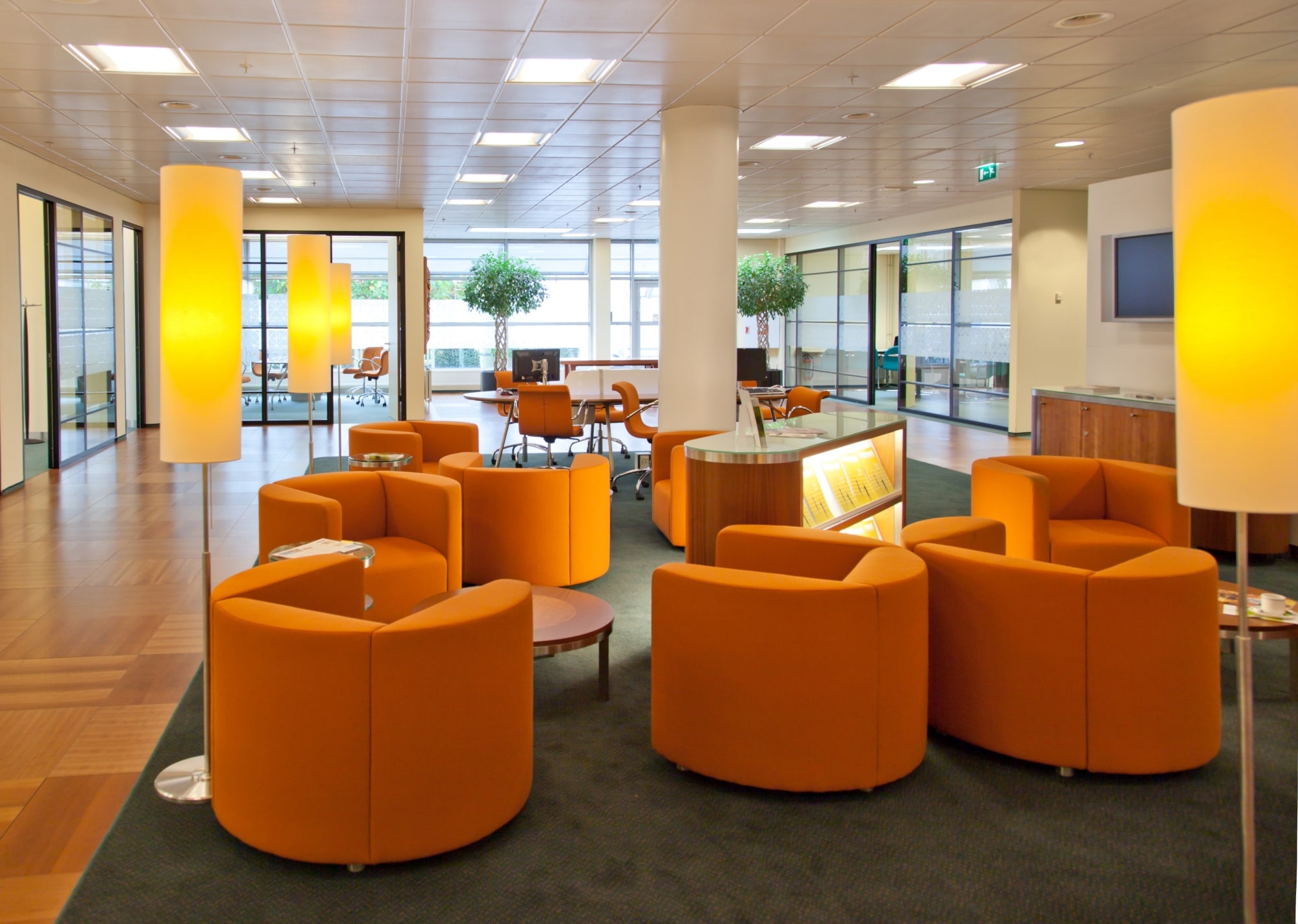A shared area in a coworking space, with bright orange tub chairs and funky lighting.