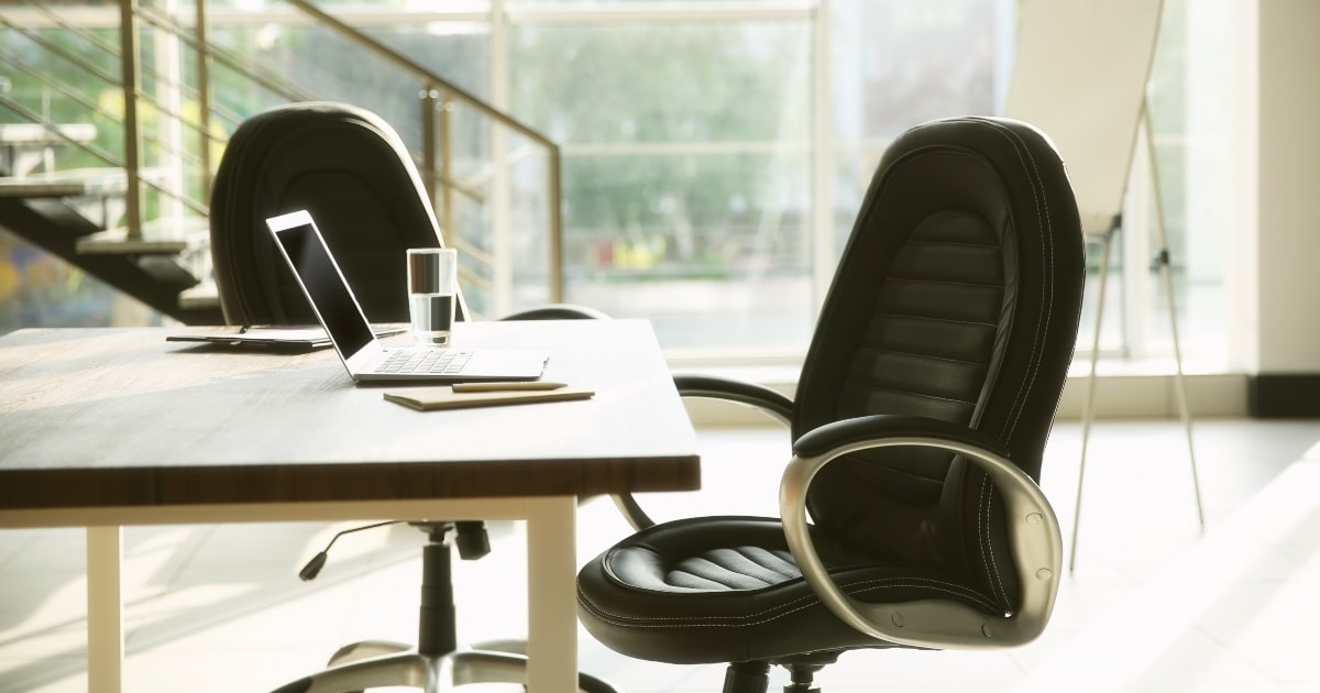 Two black leather executive chairs in stylish office.