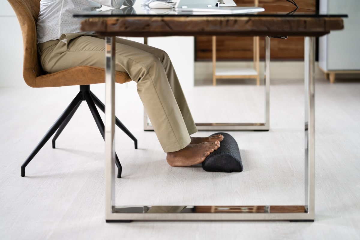 Man using a footrest at a desk to create correct posture.