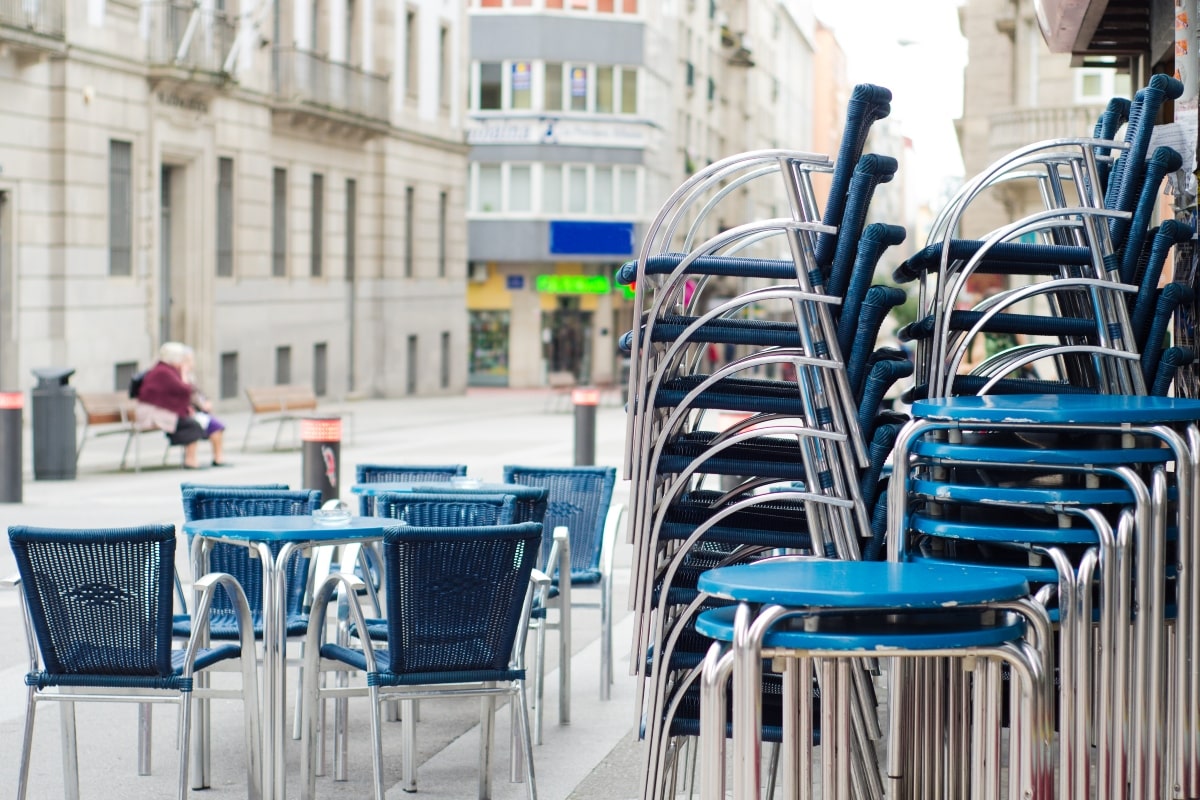 Blue chairs and stools stacked outside a cafe.