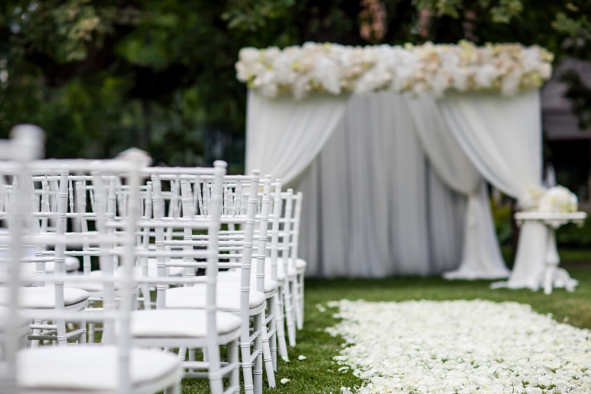 Elegant white chairs with padded seats, set up for a wedding.