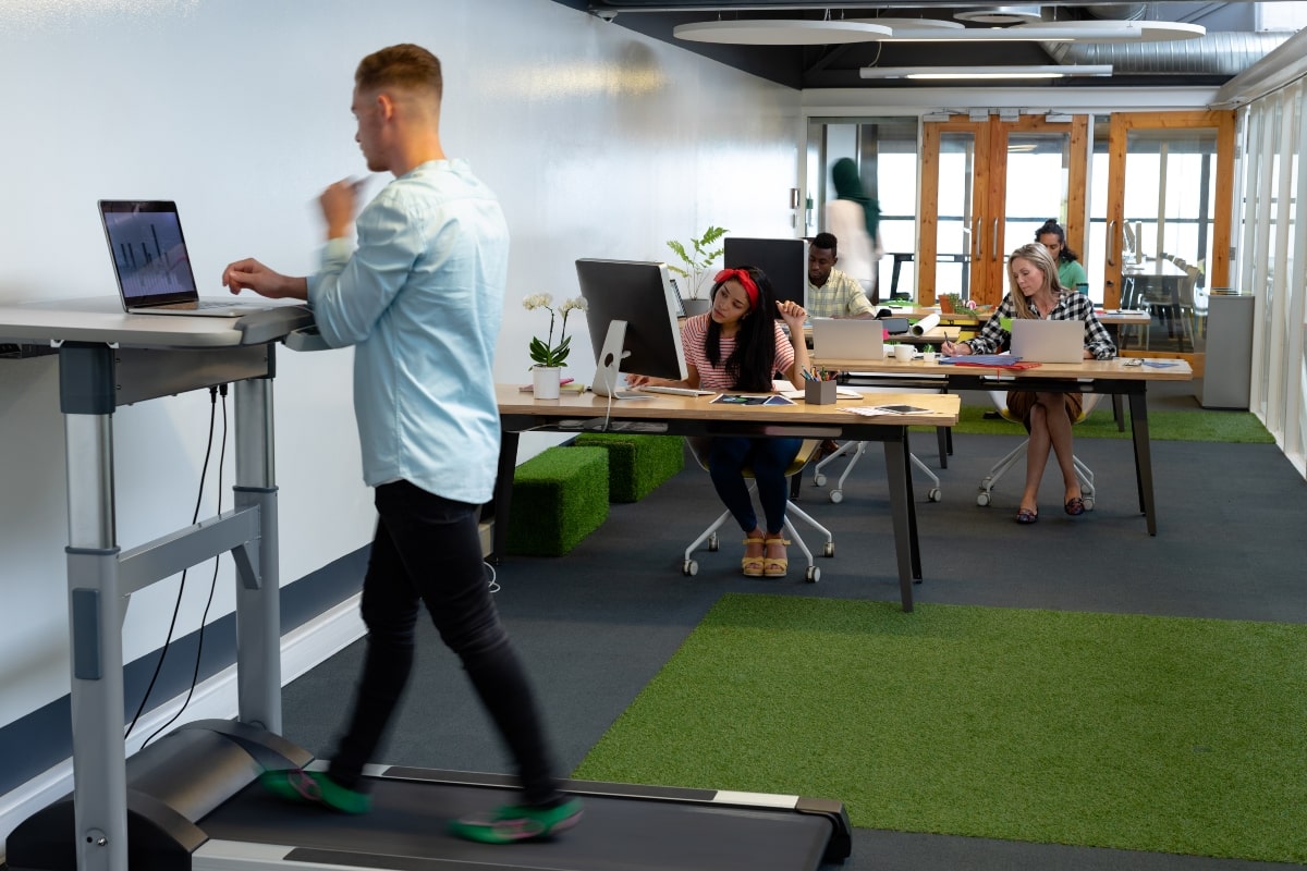 A man using a treadmill desk for exercise in his workplace to promote physical and mental health and productivity.