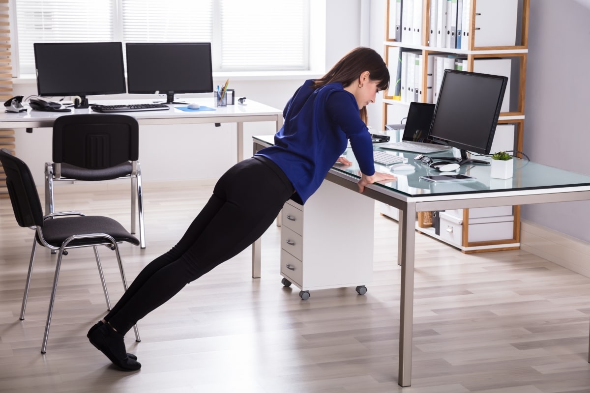 A woman doing desk push-ups as part of her desk exercise routine.