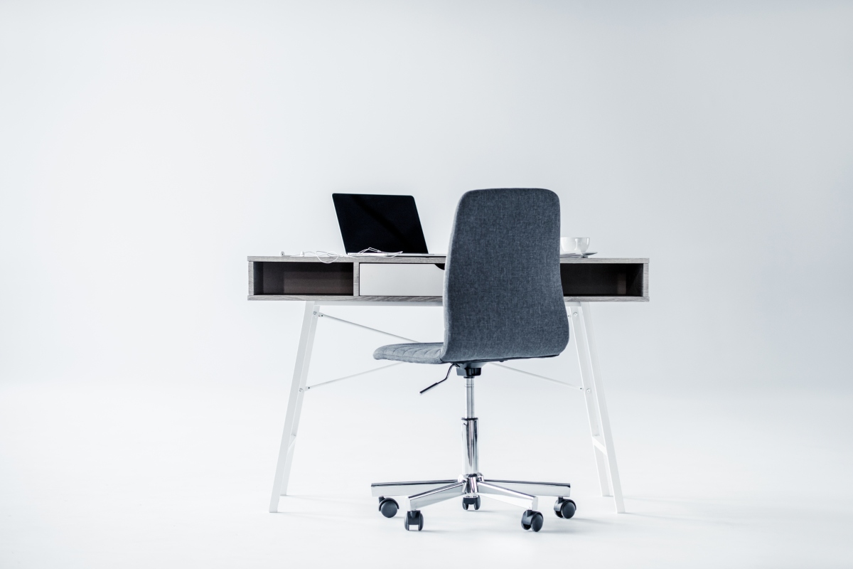 Stylish armless office chair at a desk, with a white background. 
