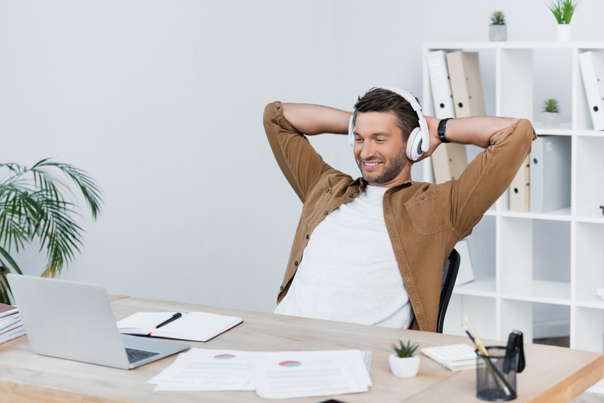 Man with headphones on sitting, happy sitting at desk.