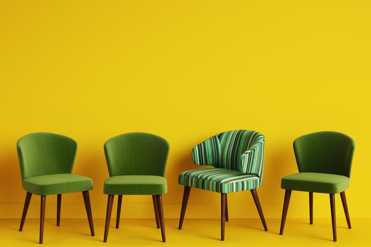 Four green fabric chairs against a vibrant yellow background, with one chair featuring a unique striped pattern, showcasing the variety of office chair fabric textures and patterns available for modern office decor.