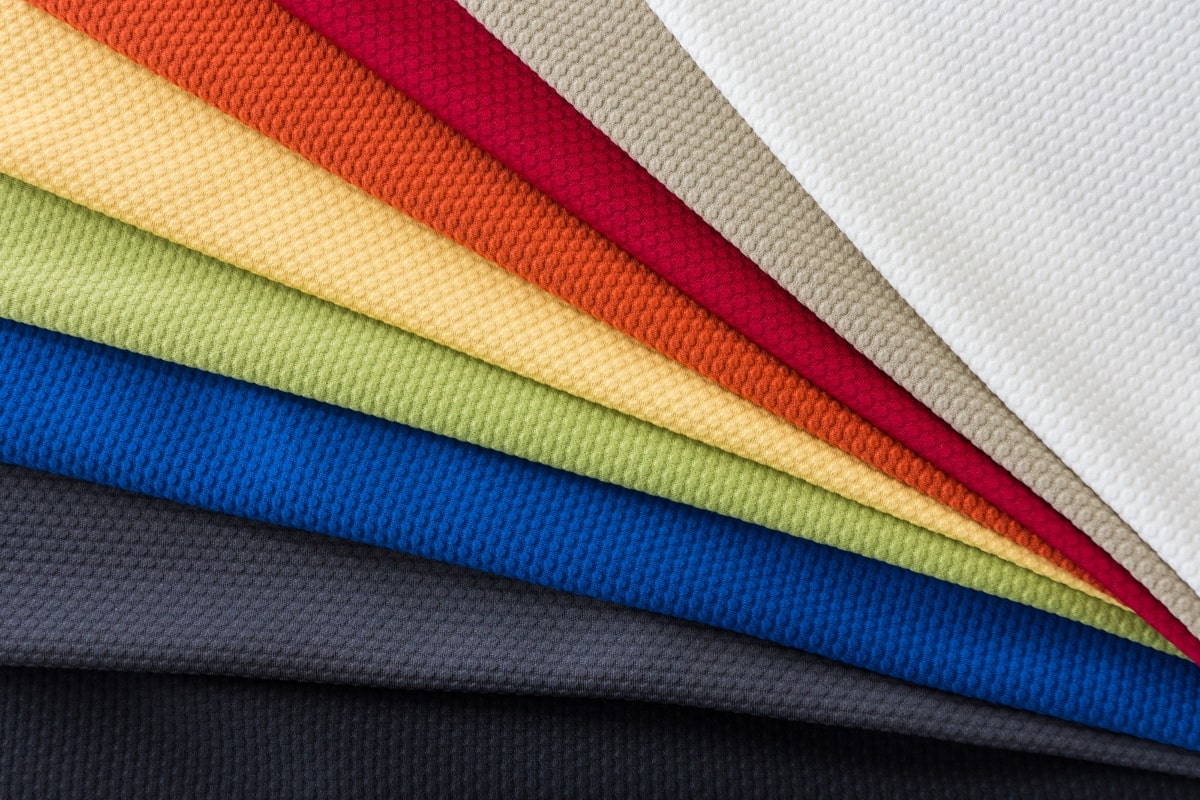 A vibrant selection of fabric samples for office chairs, arranged in a colourful spectrum from warm reds to cool blues, highlighting the variety of textures and hues available for customising office chair upholstery.